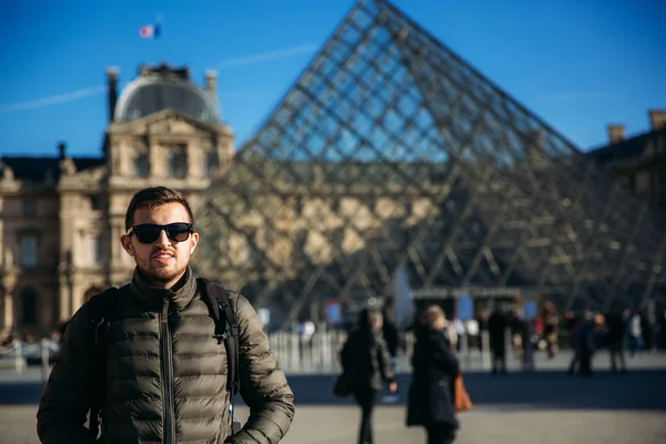 Egy fiatal férfi a khaki kabát áll a háttérben, a Louvre-ban. Őszi napsütés — Stock Fotó
