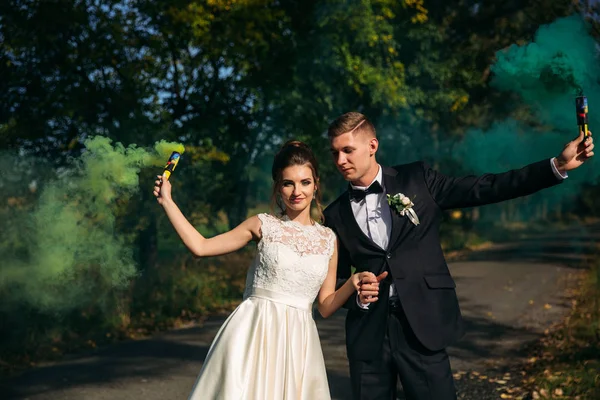 Casamento casal segurar fumaça colorida em suas mãos no meio do beco — Fotografia de Stock