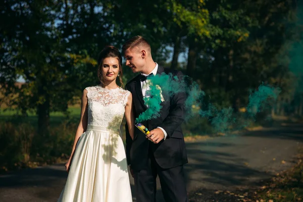 Hochzeitspaar hält mitten in Gasse farbigen Rauch in den Händen — Stockfoto