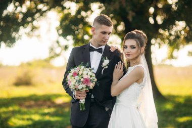 Buket ile onların düğün gününde alanına yürüme mutlu yeni evliler şık birkaç. Tarlanın ortasında ther büyük bir ağaç olduğunu.