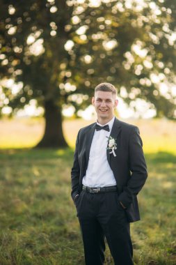 Alan büyük ağaç arka planda ortasında duran damat