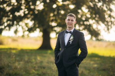 Alan büyük ağaç arka planda ortasında duran damat