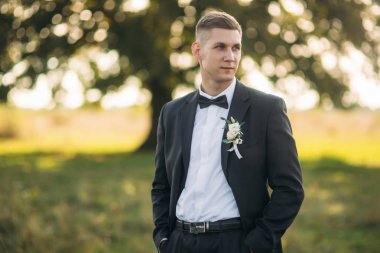 Alan büyük ağaç arka planda ortasında duran damat