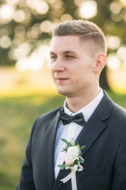 Damat papyon ayarlar. Yakışıklı adam alan büyük ağaç arka planda ortasında ayakta