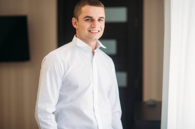 Damat takım elbiseli evde giyindi. Şirin damat bir fotoğrafçısına poz