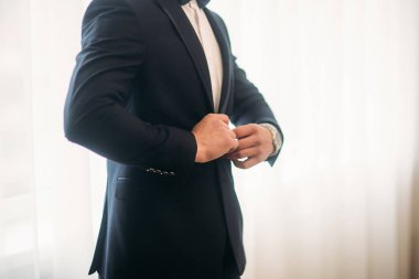 Damat takım elbiseli evde giyindi. Şirin damat bir fotoğrafçısına poz