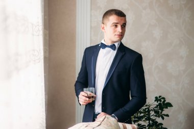 Yakışıklı adam düğün kıyafetli bir bardak viski için tutun