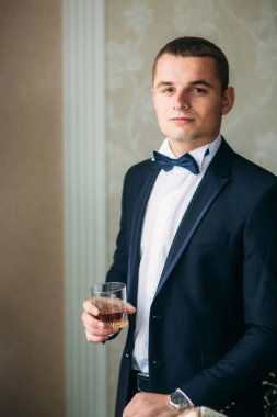 Yakışıklı adam düğün kıyafetli bir bardak viski için tutun