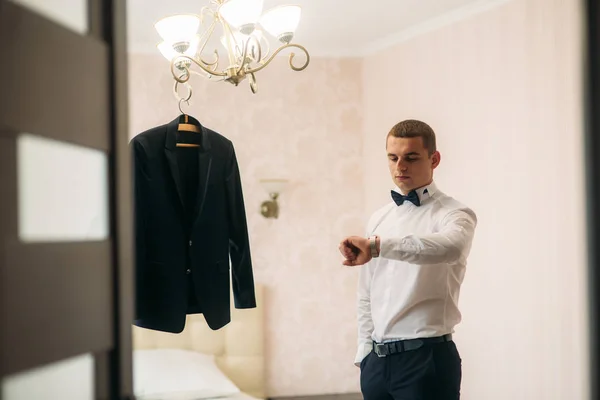 Schöner Bräutigam verwenden Uhr in Hochzeitstag — Stockfoto