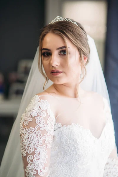 Retrato de una novia en un vestido de novia. La novia se viste en el hotel . — Foto de Stock
