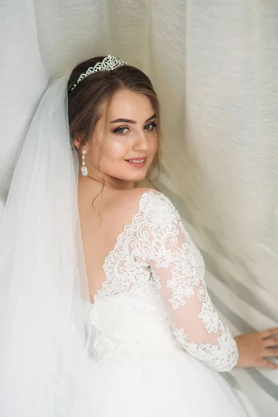 A menyasszony egy esküvői ruha alatt a fehér függöny portréja — Stock Fotó