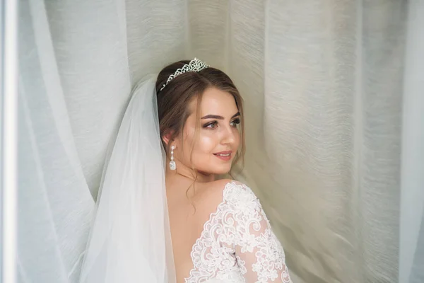 Portrait d'une mariée dans une robe de mariée sous le rideau blanc — Photo