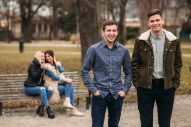 Gençler parkta iyi vakit geçiriyor. Erkek ve dişi bankta oturan ve telefonları kullanarak