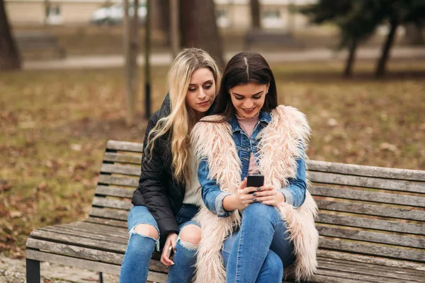 Två tjejer sitter på bänken utomhus — Stockfoto