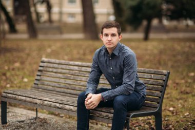 İyi adam bulutlu havalarda açık havada bankta oturmuş