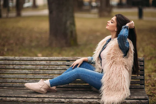 Brunette meisje zittend op het bankje in bewolkt weer — Stockfoto