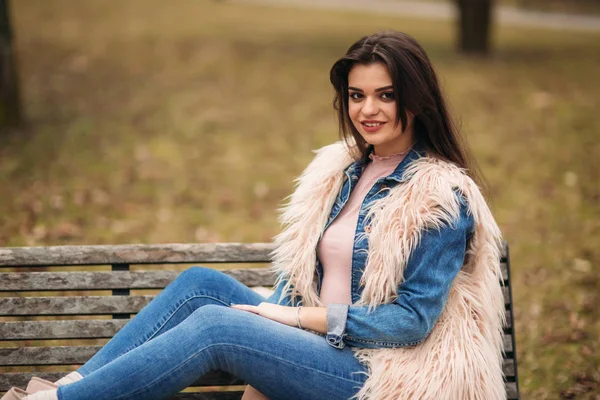 Brünettes Mädchen sitzt bei trübem Wetter auf der Bank — Stockfoto