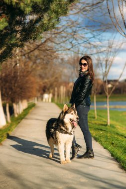 Güzel esmer Bayan ile bir köpek set boyunca yürüyüş. Güzel husky köpek