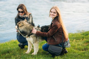 İki kız kardeş ile nehir önünde husky köpek yürümek