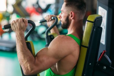 Yeşil tişörtlü trenler salonunda genç bir atlet. Vücut geliştirmeci göğüs muscules trenler