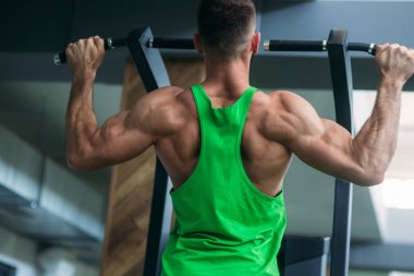 Genç bir atlet spor salonunda antrenman yapıyor. Vücut geliştirici sırt kaslarını eğitir.