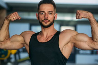 Genç bir atlet spor salonunda eğitiyor. Pazı gösterir