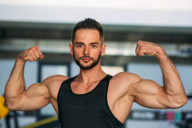 Genç bir atlet spor salonunda eğitiyor. Pazı gösterir