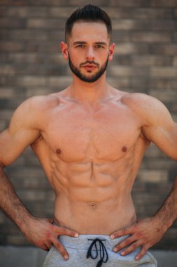 Genç atlet ile bir gövde bir tuğla duvar arka plan fotoğraf için poz. Kurtarma vücut geliştirmeci, atlet pompalanır kaslar, göğüs ve kol ile