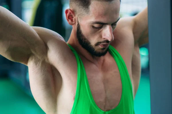 Um jovem atleta treina no ginásio. Fisiculturista treina os músculos das costas — Fotografia de Stock