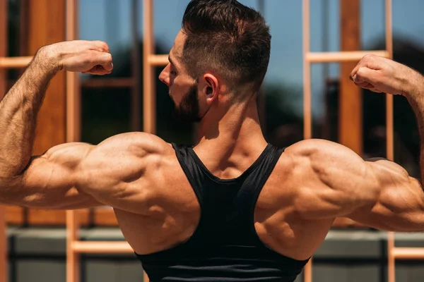 Un joven atleta entrena en el gimnasio. Muestra los músculos de la espalda —  Fotos de Stock