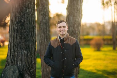 Koyu mavi gömlekli bir parkta genç bir adam. Bahar