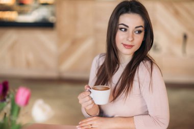 Kafede oturup kapuçino içen güzel bir kız.