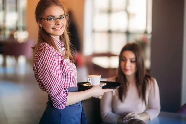 Serveerster aanbieden van een kopje koffie in het café — Stockfoto