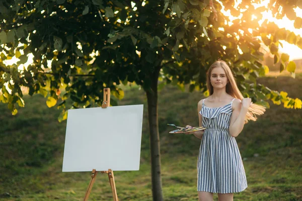 Schöne Künstlerin steht im Park und hält Palette mit Farben — Stockfoto