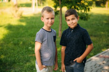 Çocuklar parkta oynuyorlar. İki güzel çocuk T-shirt ve şort gülümseyen eğlenceler