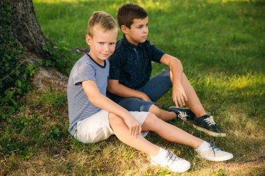 Çocuklar parkta oynuyorlar. İki güzel çocuk T-shirt ve şort gülümseyen eğlenceler