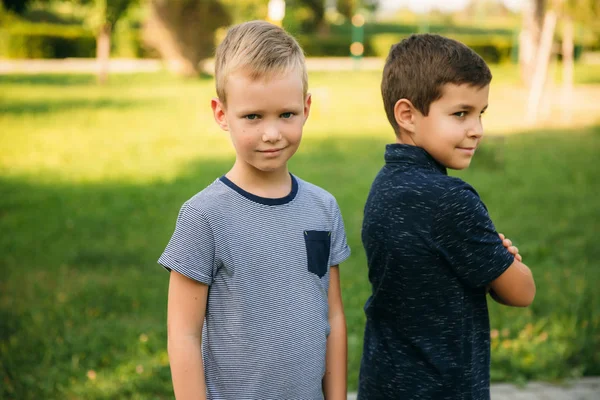 Due bambini stanno giocando nel parco. Due bei ragazzi in maglietta e pantaloncini si divertono a sorridere — Foto Stock