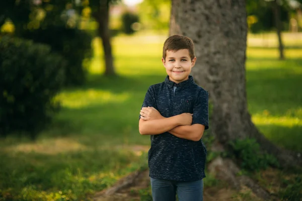 Bel ragazzo sorridente e in posa per il fotografo. Un bambino gioioso passeggia per il parco. Tempo soleggiato estate — Foto Stock
