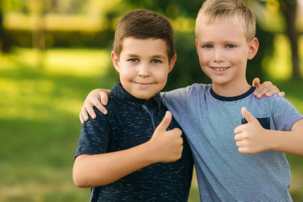 Due bambini stanno giocando nel parco. Due bei ragazzi in maglietta e pantaloncini si divertono a sorridere — Foto Stock