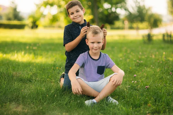 Dos niños juegan en el parque. Dos hermosos chicos en camisetas y pantalones cortos se divierten sonriendo — Foto de Stock