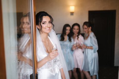 Gorgeous bride with best bridesmaids drinking champagne in hotel. Morning of bride. Sexy bridesmaids in exciting negligee