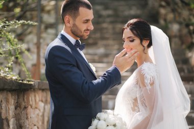 Güzel gelini ve yakışıklı damadı düğün gününde dışarıda yürüyor. Mutlu yeni evliler.