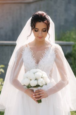 Düğününde bir buket beyaz çiçekli zarif gelinlik içinde çok güzel bir gelin.