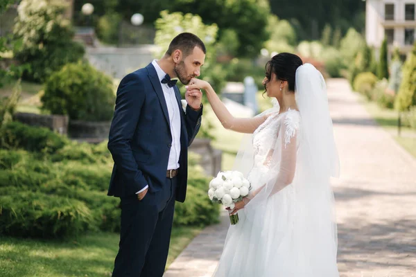 Güzel gelini ve yakışıklı damadı düğün gününde dışarıda yürüyor. Mutlu yeni evliler. — Stok fotoğraf