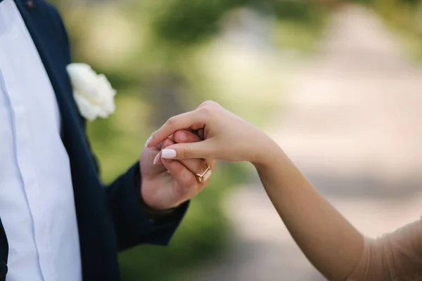 Закройте руки жениху и невесте снаружи. Жених берет невесту за руку для поцелуя — стоковое фото