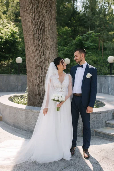 Schöne Braut mit ihrem hübschen Bräutigam, der am Hochzeitstag draußen spaziert. Glückliche Frischvermählte — Stockfoto