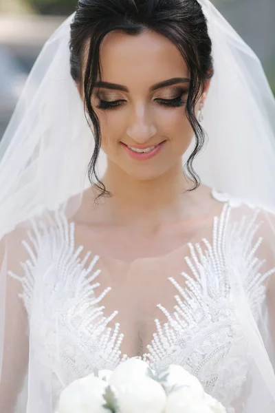 漂亮的新娘在婚礼那天穿着华丽的婚纱，开着一束白花 — 图库照片