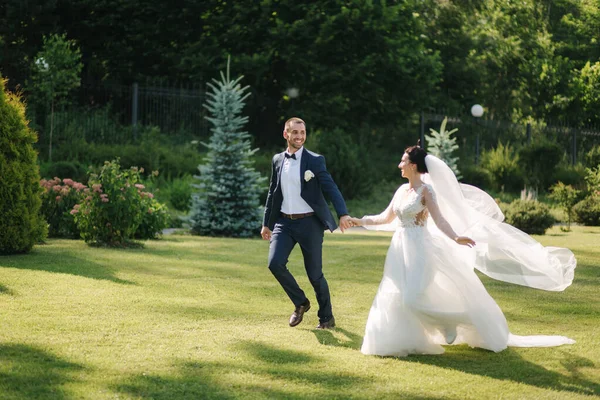 Šťastný právě ženatý pár procházející se venku ve svatební den — Stock fotografie