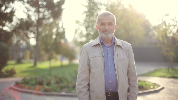 Oudere man in jasje. Oude man met baard wandelend in het herfstpark — Stockvideo