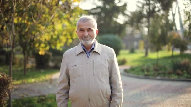 Älterer Mann in Jacke. Alter bärtiger Mann spaziert durch Herbstpark — Stockvideo